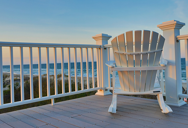 Empty Adirondack chair on a balcony deck overlooking the beach and the Gulf of America in Northwest Florida